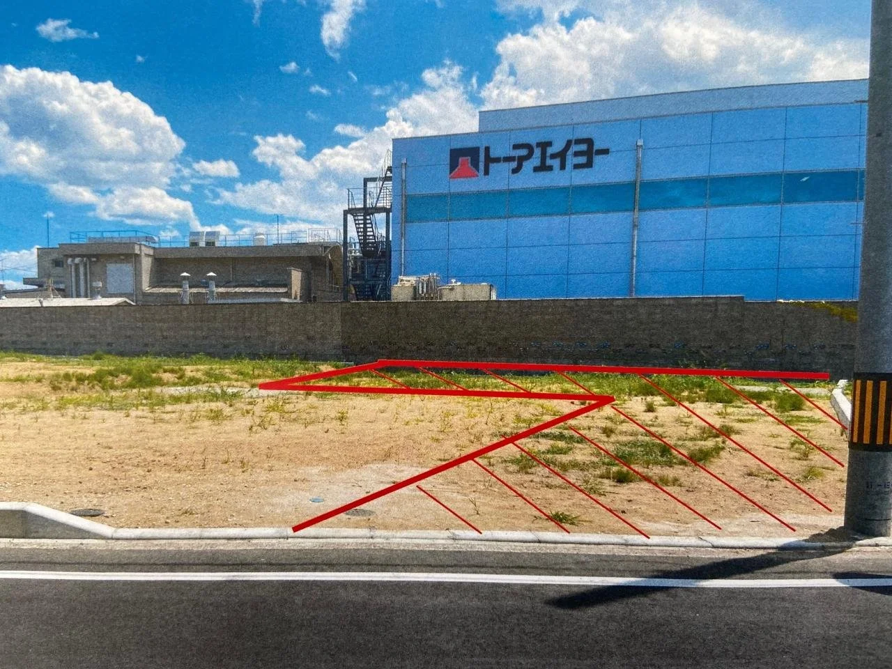 工場建物と広い空き地が続く事業用地の風景